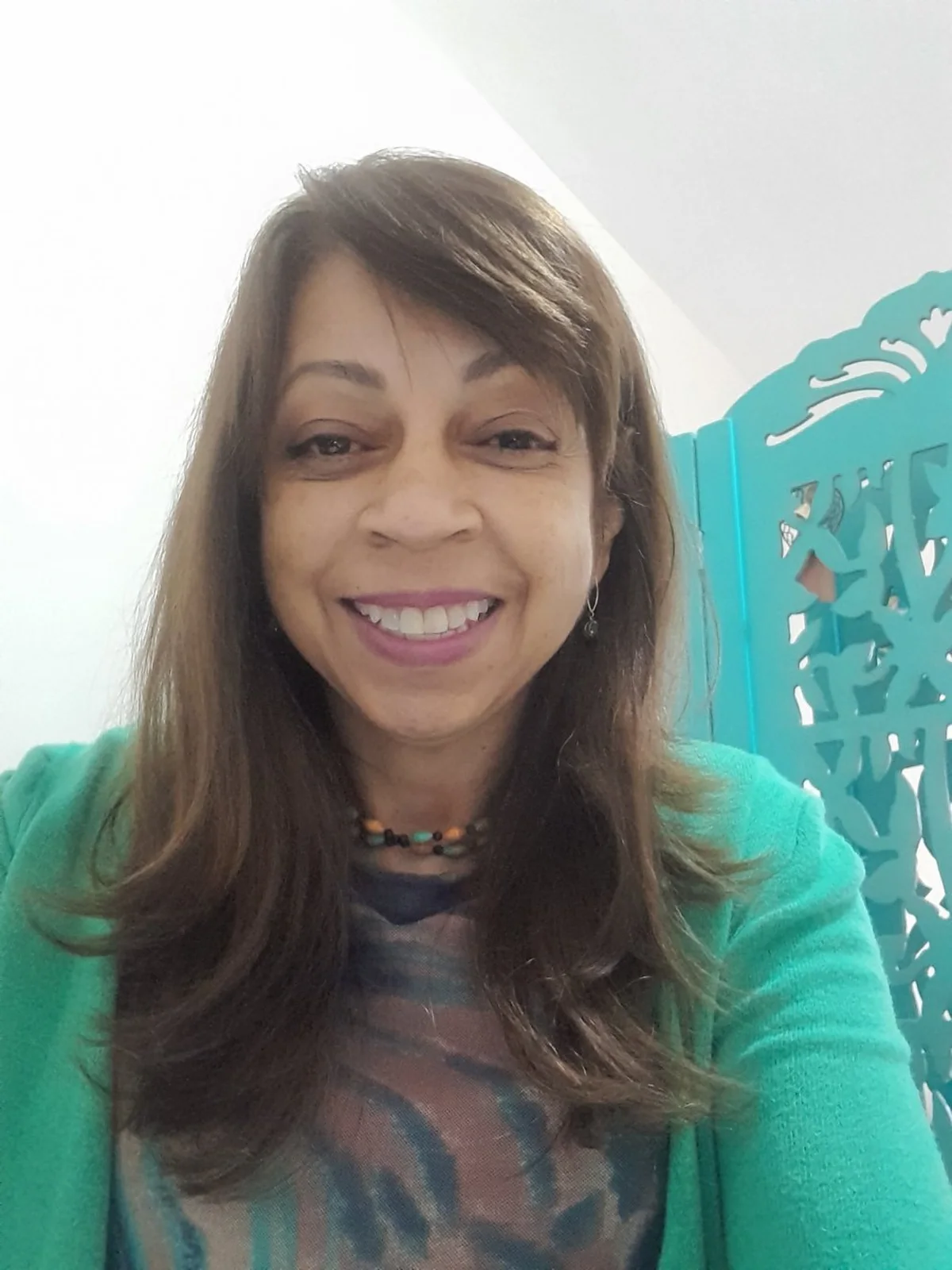 Eliane Nunes Viana sorrindo, com casaco verde e colar de contas